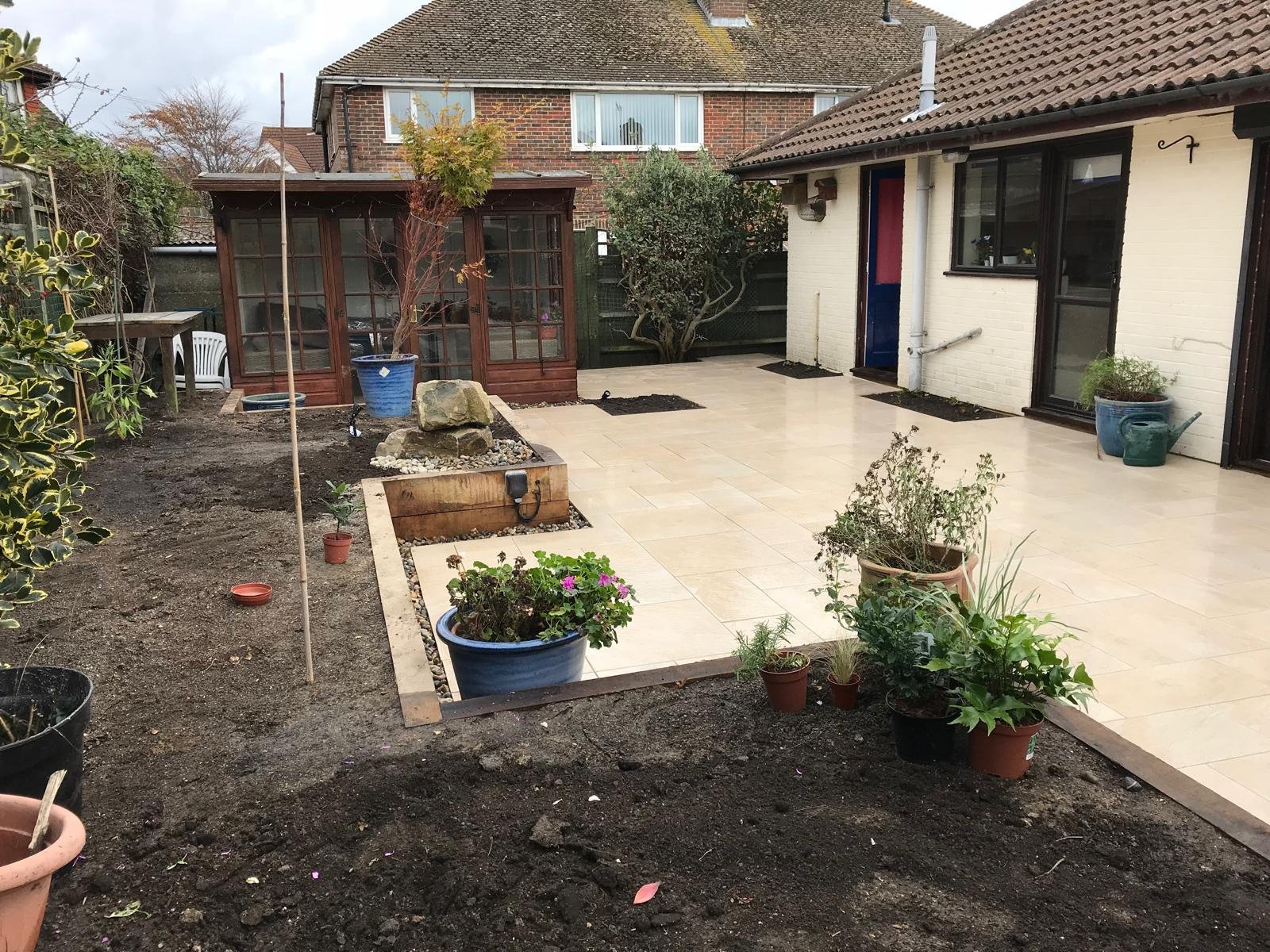 Finished patio area with cream paving and a timber summerhouse